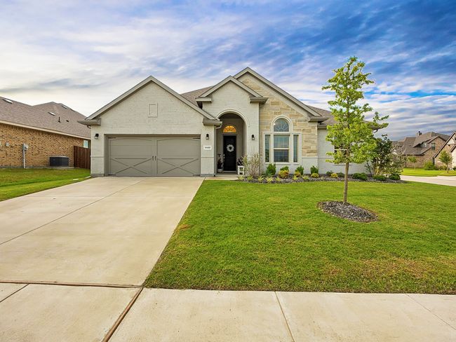View of front of home featuring a garage, a front yard, driveway, and stone siding | Image 34