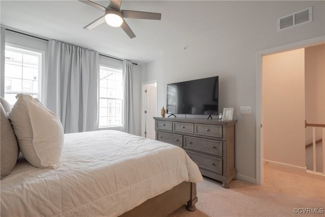 Bedroom featuring baseboards, a ceiling fan, visible vents, and light colored carpet | Image 32