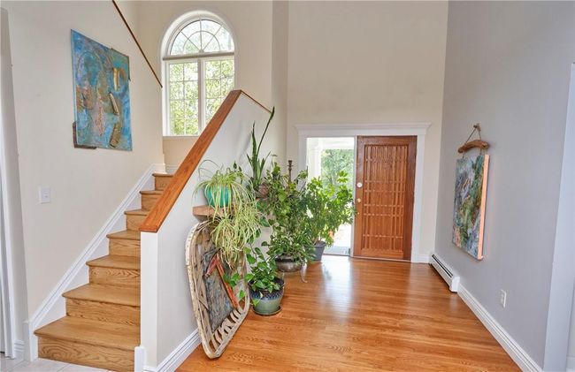 Foyer entrance with a baseboard radiator, plenty of natural light, light hardwood / wood-style flooring, and a high ceiling | Image 10