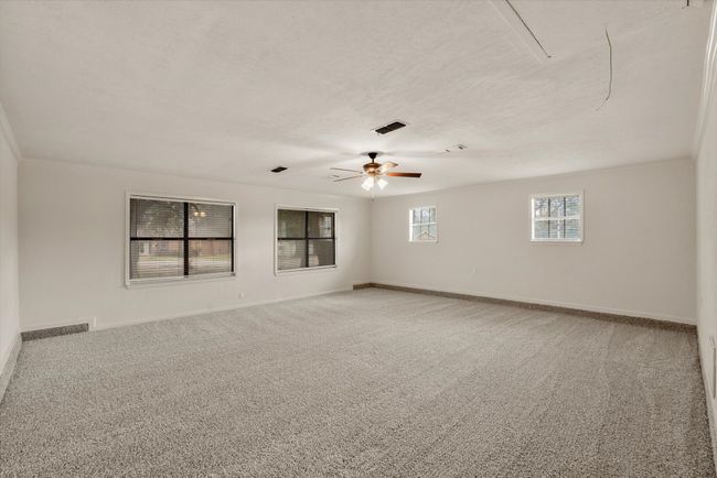 Carpeted spare room with ceiling fan, crown molding, and a textured ceiling | Image 11
