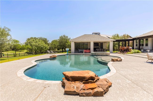 View of swimming pool featuring a patio, fence, a gazebo, and a pool with connected hot tub | Image 19
