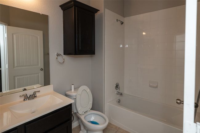 Bathroom with toilet, vanity, shower / bathtub combination, tile patterned floors, and baseboards | Image 6