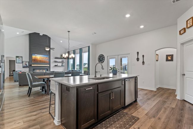 Kitchen featuring dark brown cabinets, a sink, dishwasher, a large fireplace, and light wood finished floors | Image 18