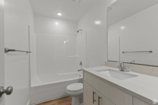 Bathroom with wood finished floors, visible vents, toilet, vanity, and shower / bathtub combination | Image 13