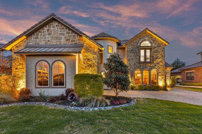 View of front of property featuring stone siding, a standing seam roof, a front lawn, and a balcony | Image 30