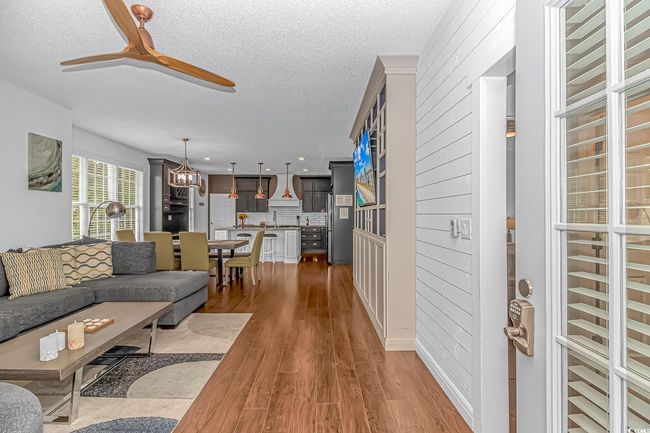 Living room featuring a textured ceiling, wood finished floors, a ceiling fan, a chandelier, and recessed lighting | Image 4