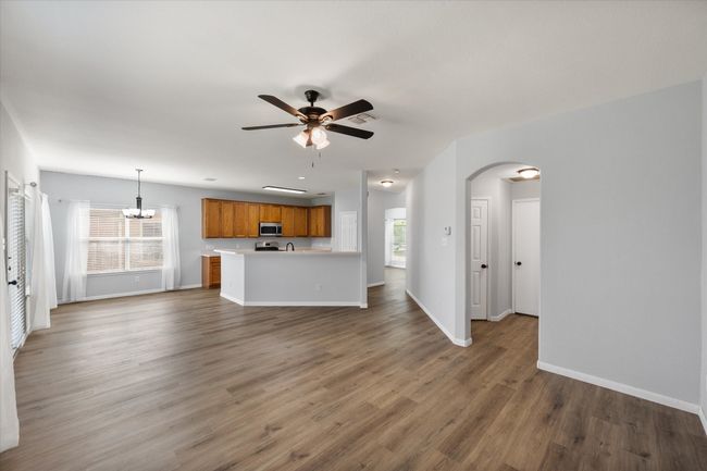 Unfurnished living room featuring ceiling fan, arched walkways, healthy amount of natural light, and a chandelier | Image 19
