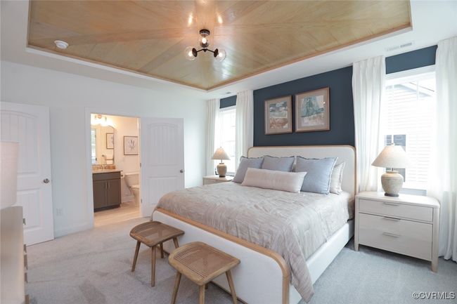 The private, first-floor primary suite is tucked away at the back of the home and offers a tray ceiling, walk-in closet and an ensuite bath with luxury shower and double vanity. | Image 4