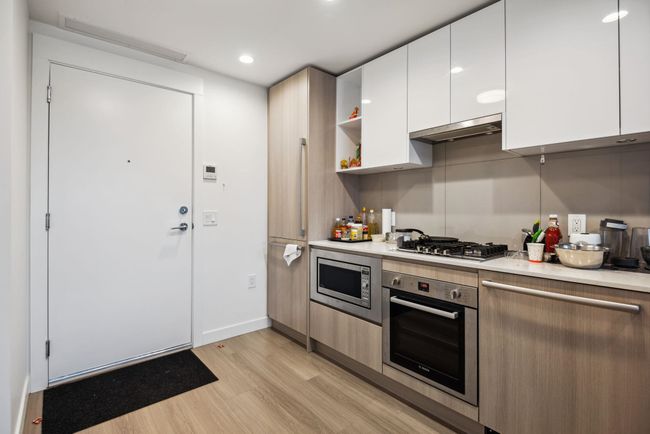 Kitchen featuring white cabinetry, under cabinet range hood, light countertops, and stainless steel appliances | Image 5