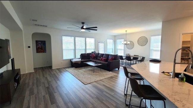 Living area featuring dark wood-style floors, a ceiling fan, healthy amount of natural light, and a chandelier | Image 16