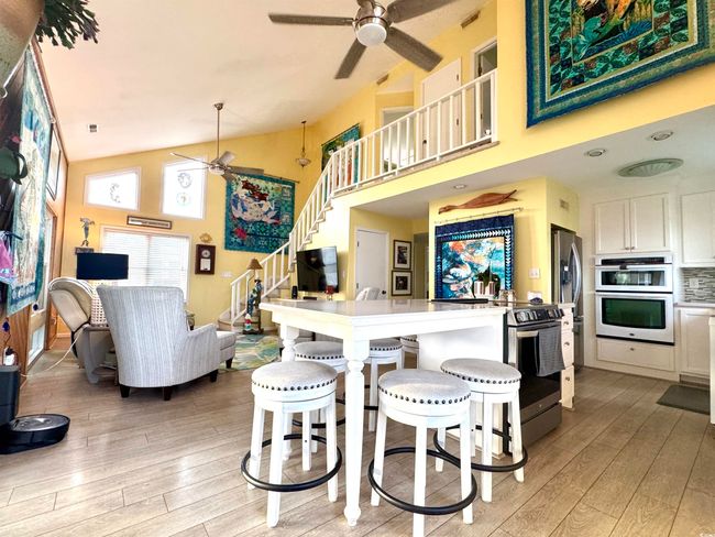 Kitchen featuring a ceiling fan, stainless steel appliances, light wood finished floors, high vaulted ceiling, and white cabinetry | Image 17