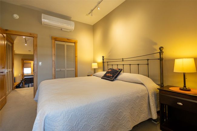 Carpeted bedroom featuring a wall mounted air conditioner, vaulted ceiling, a closet, and track lighting | Image 14