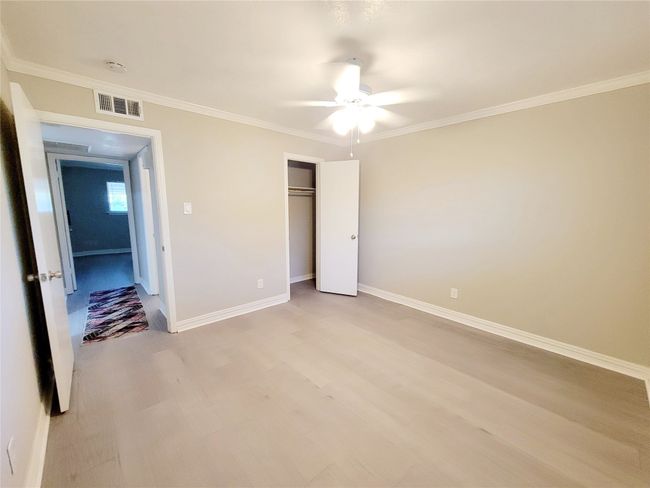 Unfurnished bedroom with light wood-type flooring, a closet, ceiling fan, and ornamental molding | Image 17