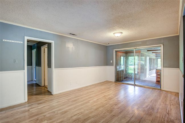 Unfurnished room featuring ornamental molding, wood finished floors, a textured ceiling, and wainscoting | Image 4