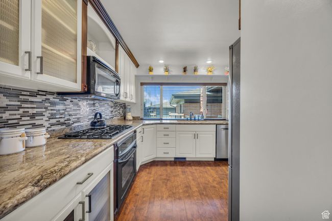 Kitchen with recessed lighting, black appliances, backsplash, and dark wood finished floors | Image 12