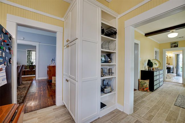 Hallway with light wood-style floors, visible vents, baseboards, and ornamental molding | Image 15