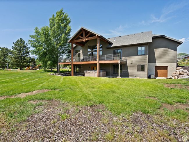 Rear view of property featuring a jacuzzi, a yard, roof with shingles, and a deck | Image 58