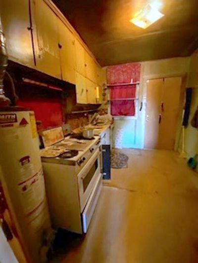 Kitchen with white range, water heater, and concrete floors | Image 3