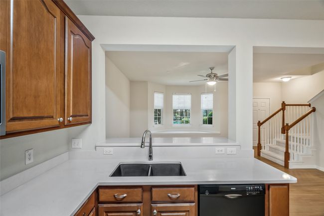 Kitchen featuring light wood-type flooring, black dishwasher, light countertops, and a sink | Image 10