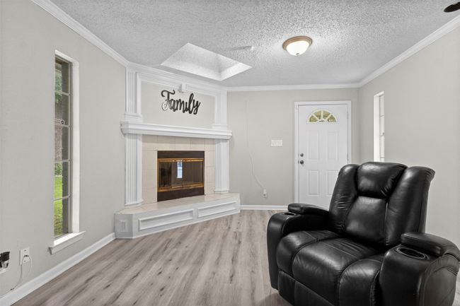 Living room featuring a textured ceiling, a skylight, wood finished floors, and a fireplace | Image 8