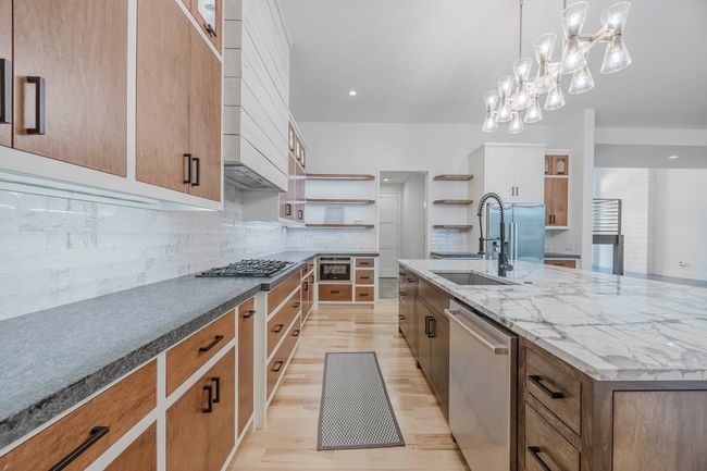 Kitchen featuring tasteful backsplash, stainless steel appliances, light wood-style floors, recessed lighting, and a large island | Image 8