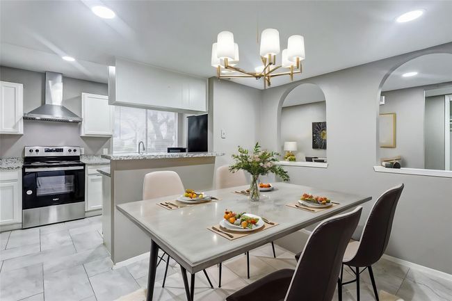 The sleek kitchen boasts modern updates with granite countertops, stainless steel appliances, and white cabinetry. A raised breakfast bar overlooks the open living area, making it easy to entertain or share meals. Bright recessed lighting ensures the space feels light and welcoming, while the open layout ties the kitchen seamlessly to the rest of the home. | Image 6