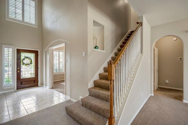 As you move back out into the living room, this view captures the archway just to the right of the stairs leading to the primary suite. The front door is visible on the left, with the study located just to the left of the stairs, creating a well-connected and inviting layout. | Image 16