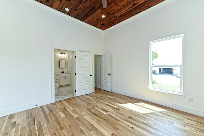 Master bedroom with wooden ceiling, crown molding, light wood-style floors, and ensuite bathroom | Image 28