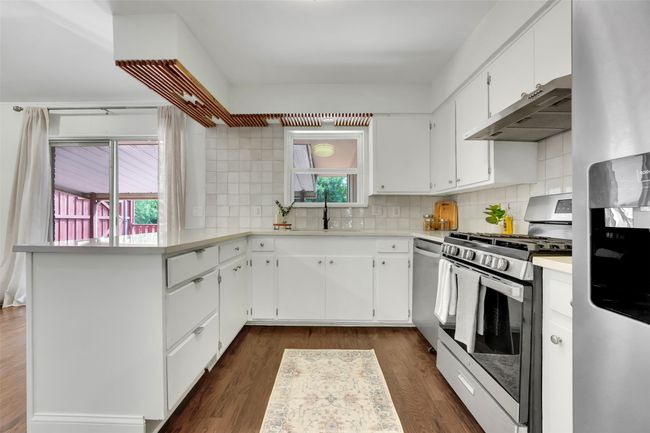 Kitchen featuring stainless steel appliances, exhaust hood, a peninsula, and light countertops | Image 11