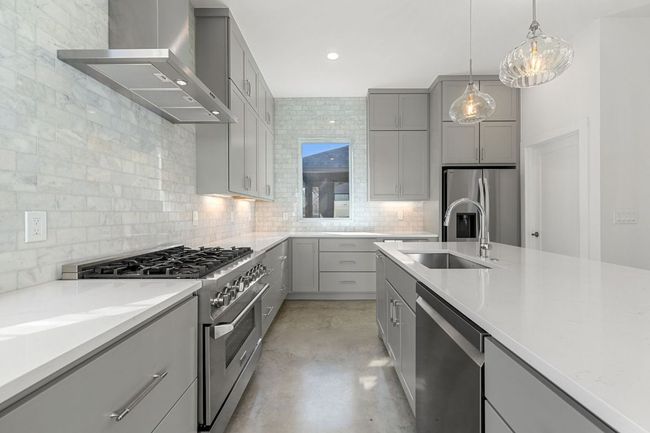 Kitchen with decorative backsplash, exhaust hood, stainless steel appliances, gray cabinetry, and a sink | Image 15