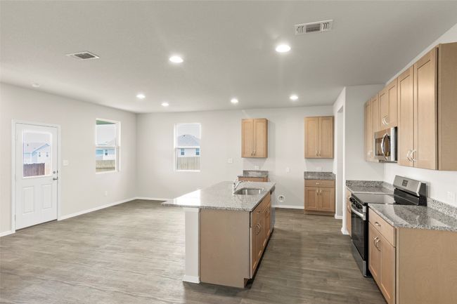 Kitchen with appliances with stainless steel finishes, a kitchen island with sink, recessed lighting, light stone counters, and dark wood-type flooring | Image 20