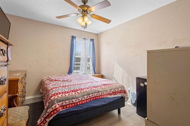 Bedroom featuring baseboards, wood finished floors, a textured wall, and a ceiling fan | Image 22