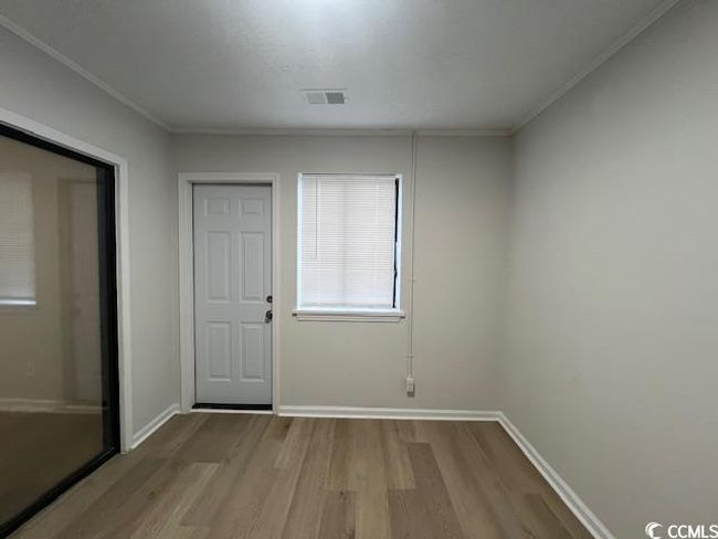 Doorway with baseboards, visible vents, ornamental molding, and wood finished floors | Image 9