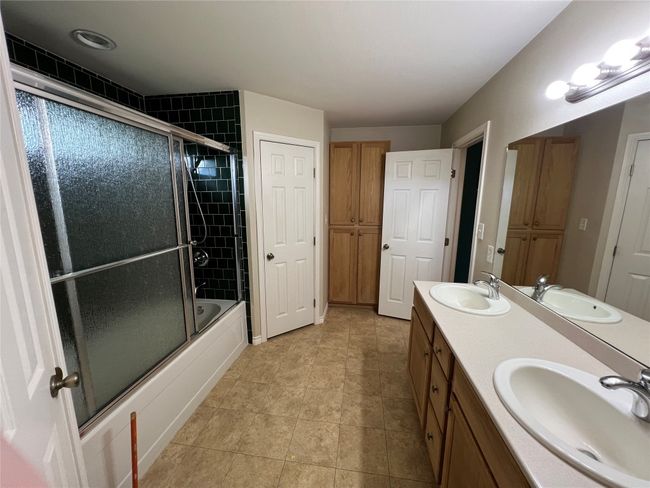 Full bath with combined bath / shower with glass door, tile patterned flooring, and double vanity | Image 16