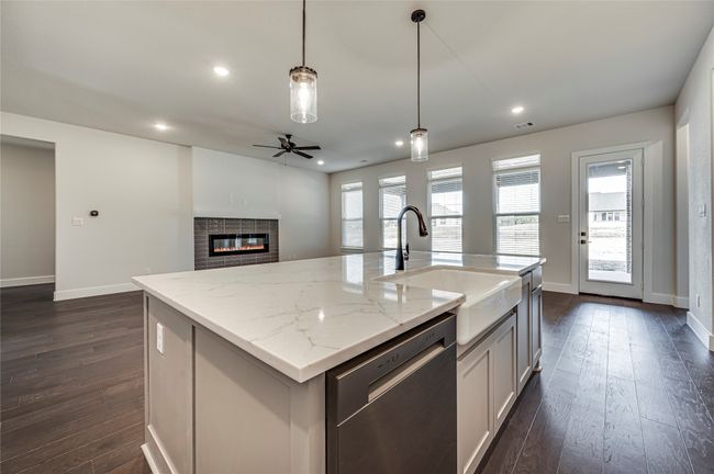 Kitchen with dishwasher, a sink, a ceiling fan, light stone countertops, and dark wood-type flooring | Image 7