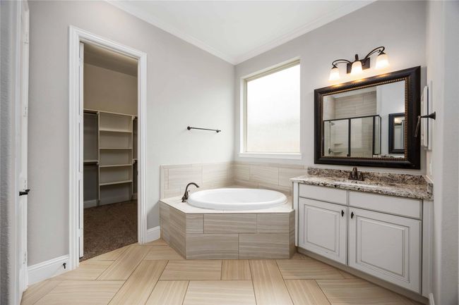 The bathroom also has a corner bathtub, granite countertop, and elegant cabinetry adjacent to a walk-in closet. | Image 23