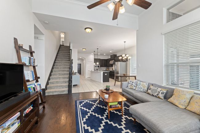 Living area featuring ceiling fan, light wood finished floors, stairs, a chandelier, and arched walkways | Image 15