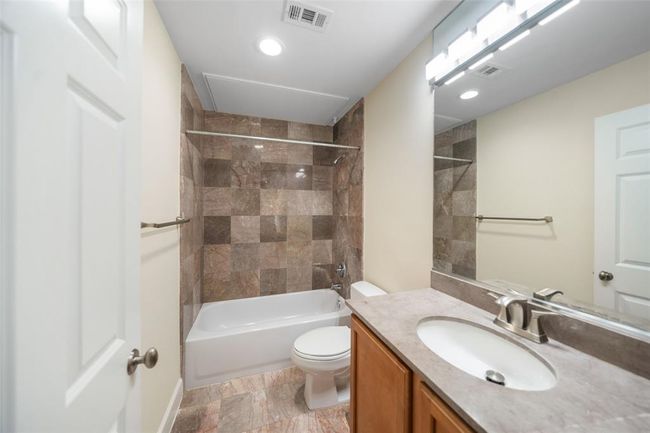 Elegant guest bathroom featuring travertine vanity top, modern fixtures and stylish tile accents. | Image 30