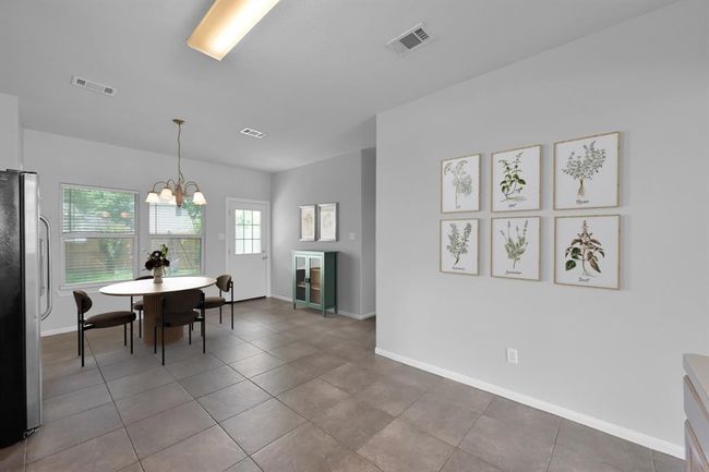 The adjacent dining space is highlighted by a charming chandelier, windows overlooking the backyard, and direct access to the backyard.*Virtually staged | Image 13