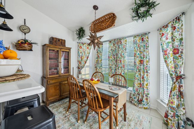 Dining room featuring healthy amount of natural light, light tile patterned floors, vaulted ceiling, and a textured ceiling | Image 14