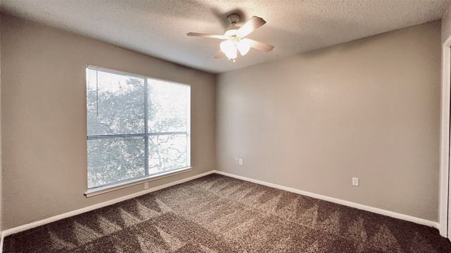 Carpeted empty room featuring healthy amount of natural light, a ceiling fan, a textured ceiling, and baseboards | Image 9