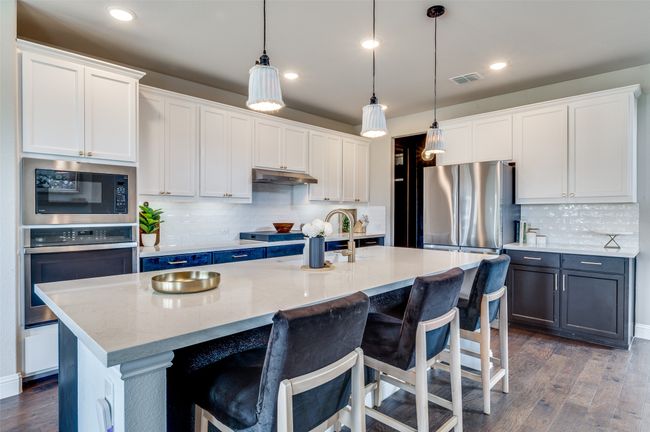 Kitchen featuring dark wood-type flooring, visible vents, under cabinet range hood, a sink, and stainless steel appliances | Image 10