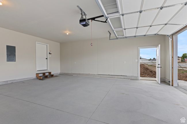 Garage featuring electric panel, a garage door opener, and baseboards | Image 22