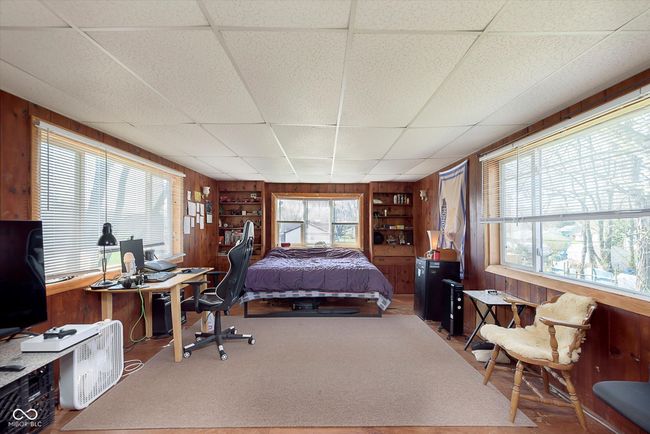 bedroom with wood walls, multiple windows, and carpet floors | Image 19