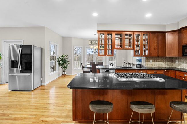 This open-concept chef’s kitchen impresses with a large center island, granite counters, and panoramic views through sunlit breakfast nook windows. 2nd fridge may remain. | Image 9