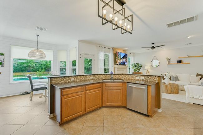 Kitchen with stainless steel dishwasher, a sink, open floor plan, ceiling fan, and light tile patterned flooring | Image 11