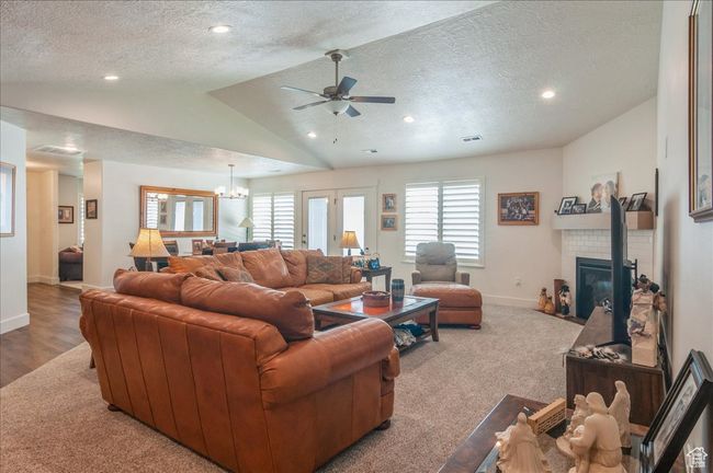 Living room with vaulted ceiling, a textured ceiling, baseboards, a ceiling fan, and a tile fireplace | Image 13