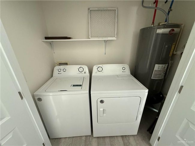 Laundry room featuring water heater, washing machine and clothes dryer, and light wood-type flooring | Image 7