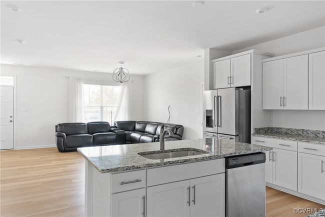 Kitchen with appliances with stainless steel finishes, a center island with sink, a sink, white cabinets, and light wood finished floors | Image 13