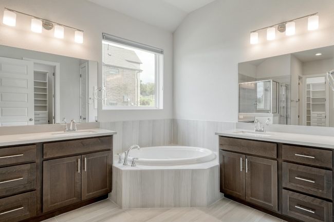 Full bathroom featuring a shower stall, a spacious closet, two vanities, a bath, and lofted ceiling | Image 18